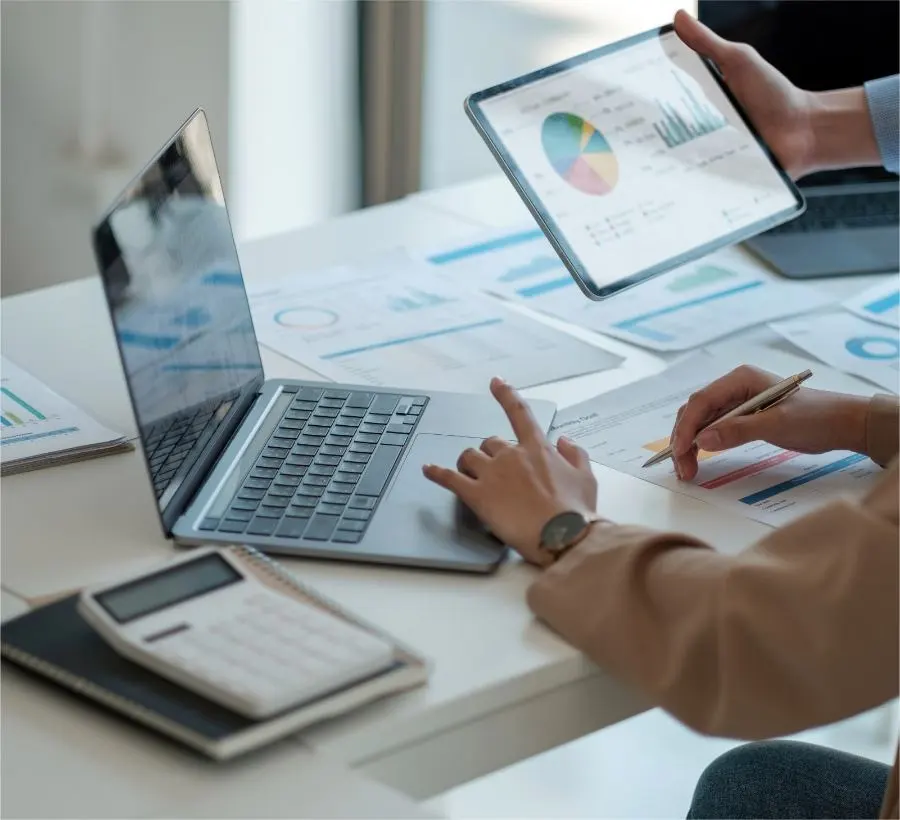 Picture of a laptop and various graphics lying on the table during a meeting.