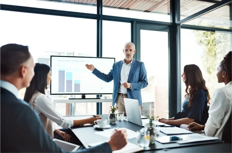 A man gives a presentation to a group of listeners in a conference room.