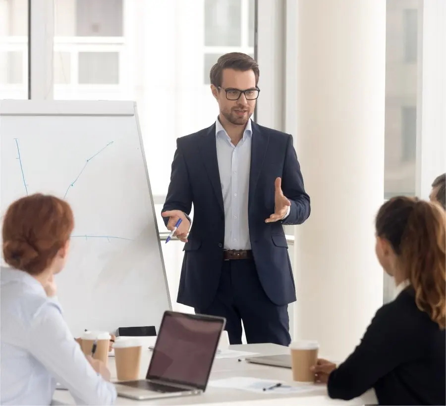 A man in a suit gives a presentation to his team in a modern conference room.