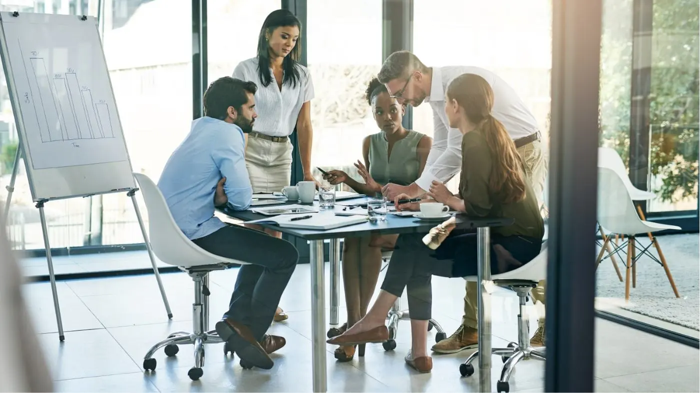 Picture of five people at an office table during a meeting.