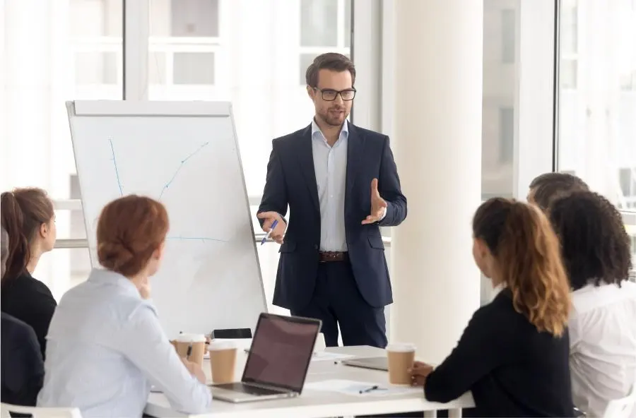 A man in a suit gives a presentation to his team.