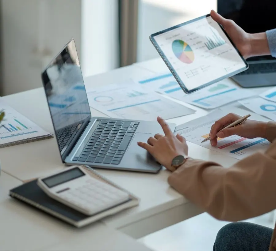 Image of a laptop and various graphics lying on a table during a meeting.