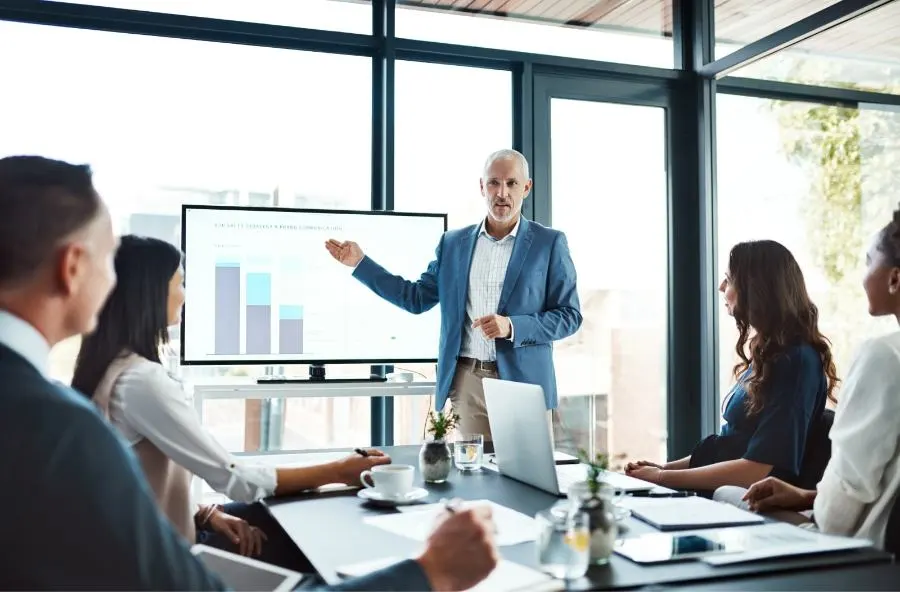 A man gives a presentation to a group of listeners in a conference room.